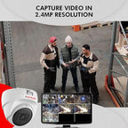 Three men in a warehouse setting with a camera and monitor displaying video footage.

