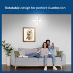 Couple sitting on a couch with a framed picture above them, featuring text about rotatable design for perfect illumination.


