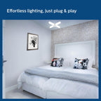 Bedroom with a bed featuring decorative pillows and a light fixture on the wall.

