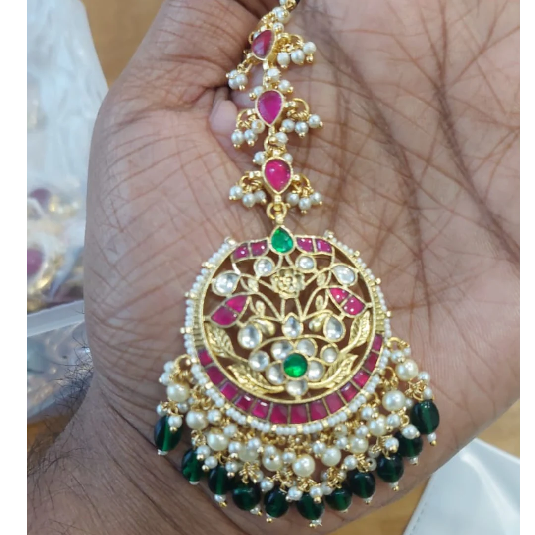 Decorative gold pendant with pearls and gemstones on a hand

