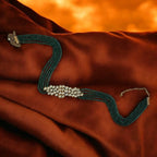 Green beaded necklace on a rust-colored fabric background

