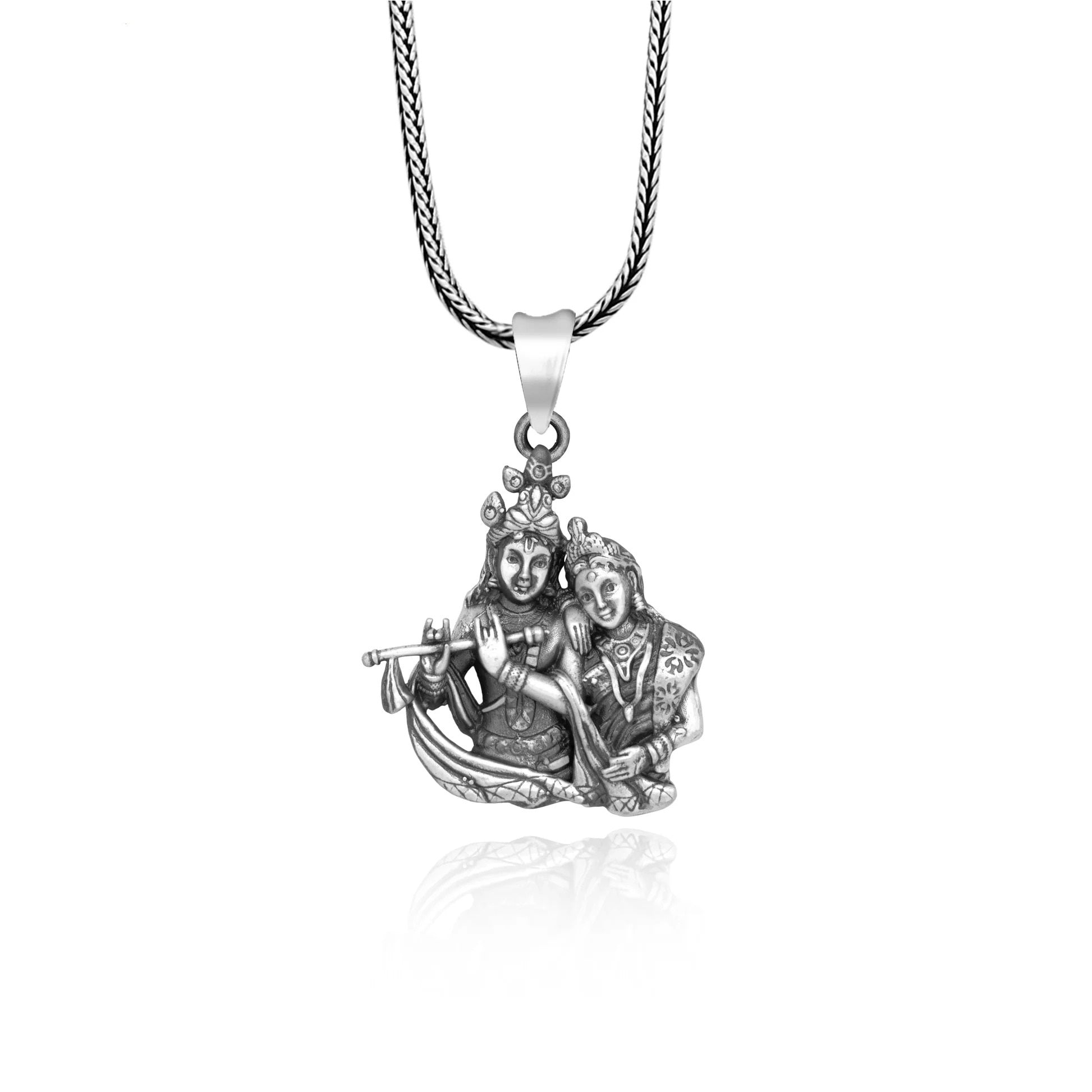 Silver pendant with two figures on a white background


